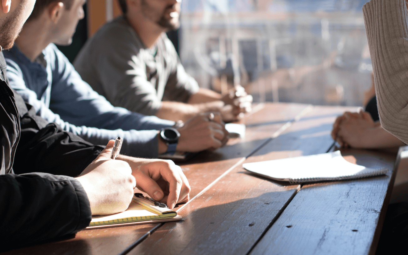 people sitting at a table together in discussion, taking notes.