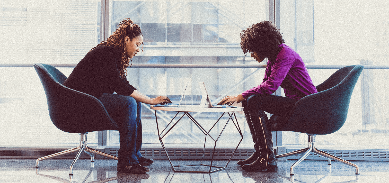 Two women working on laptops at a table together