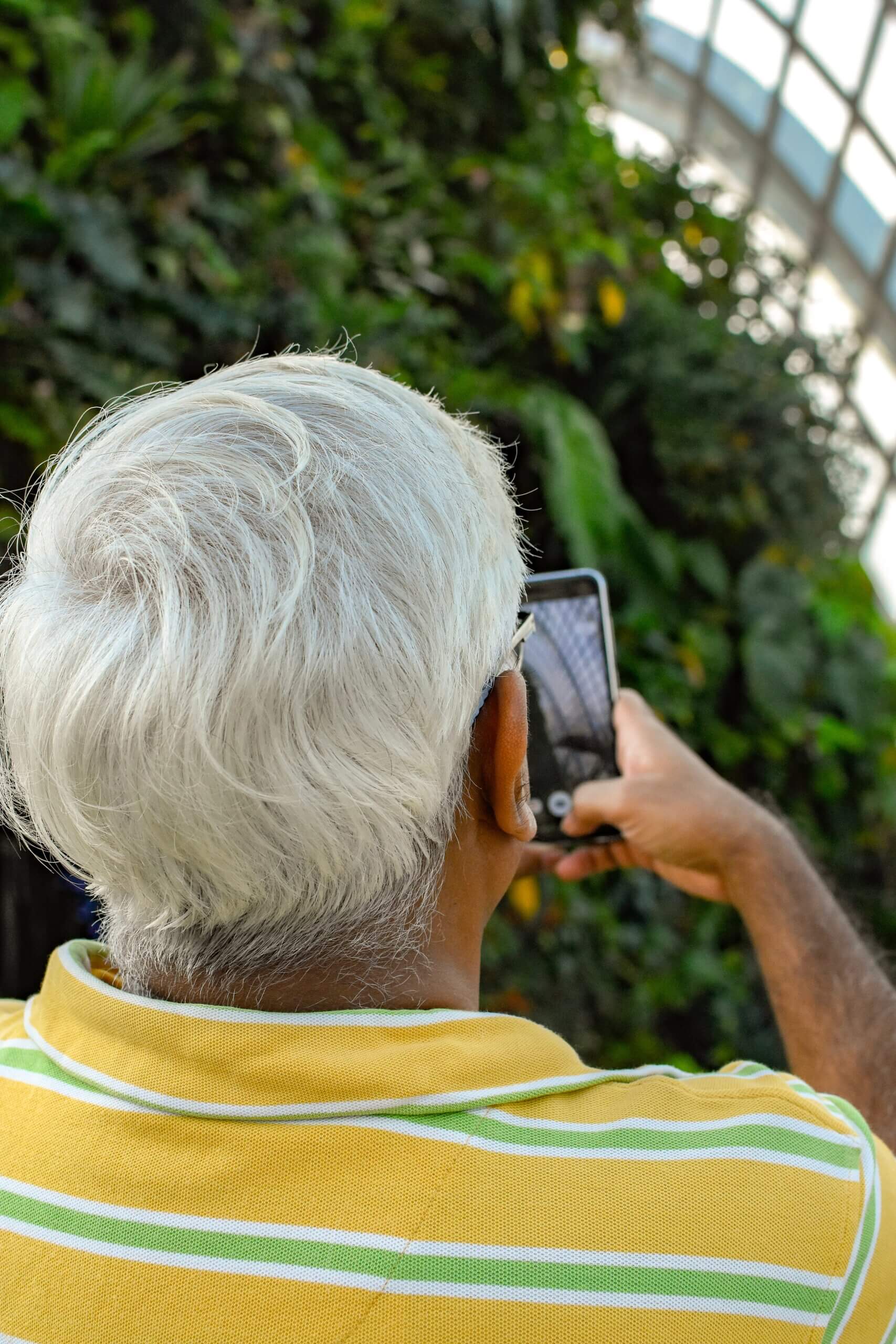 Elderly man taking cellphone photo