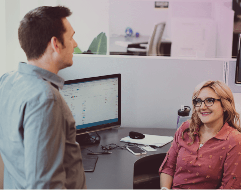 Two coworkers chatting at their desk