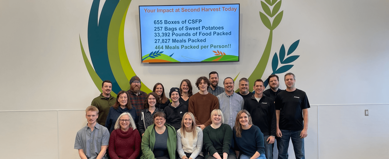 Creed team at Second Harvest in front of a screen of data about how they helped