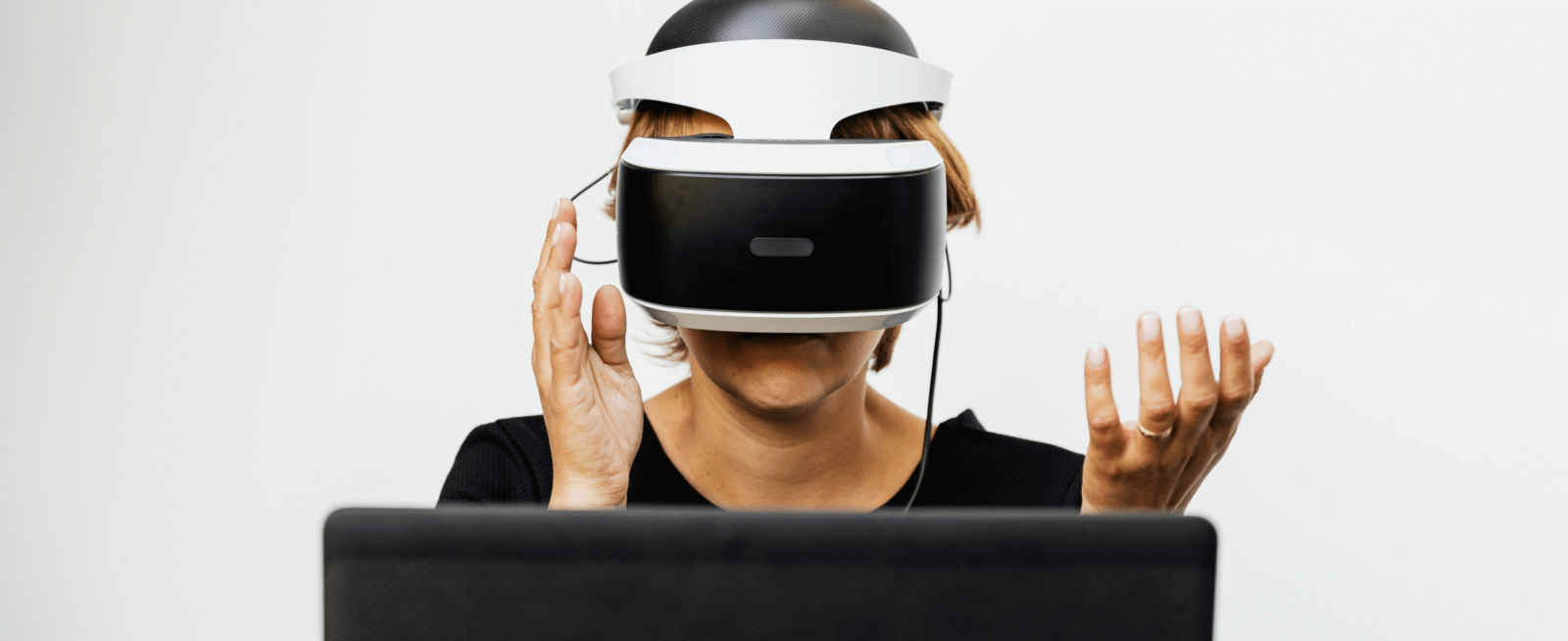 person wearing a vr headset in front of a laptop