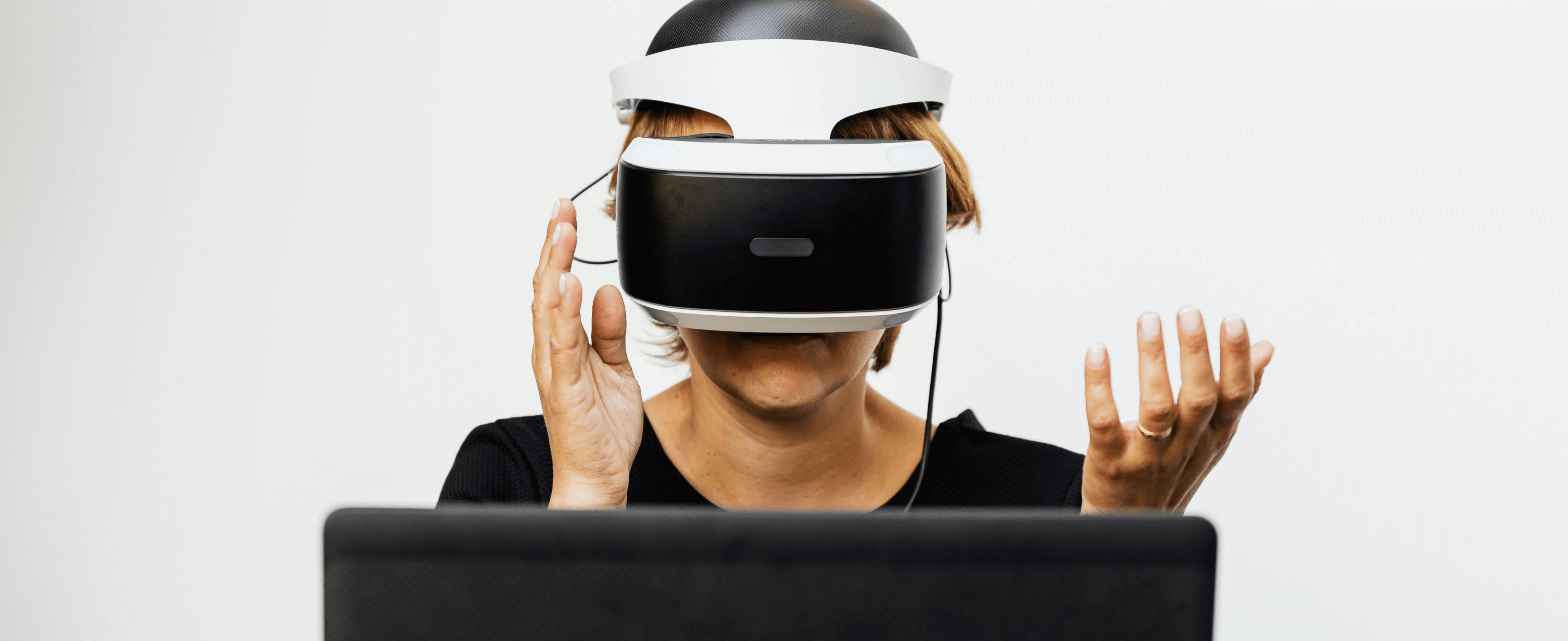 person wearing a vr headset in front of a laptop