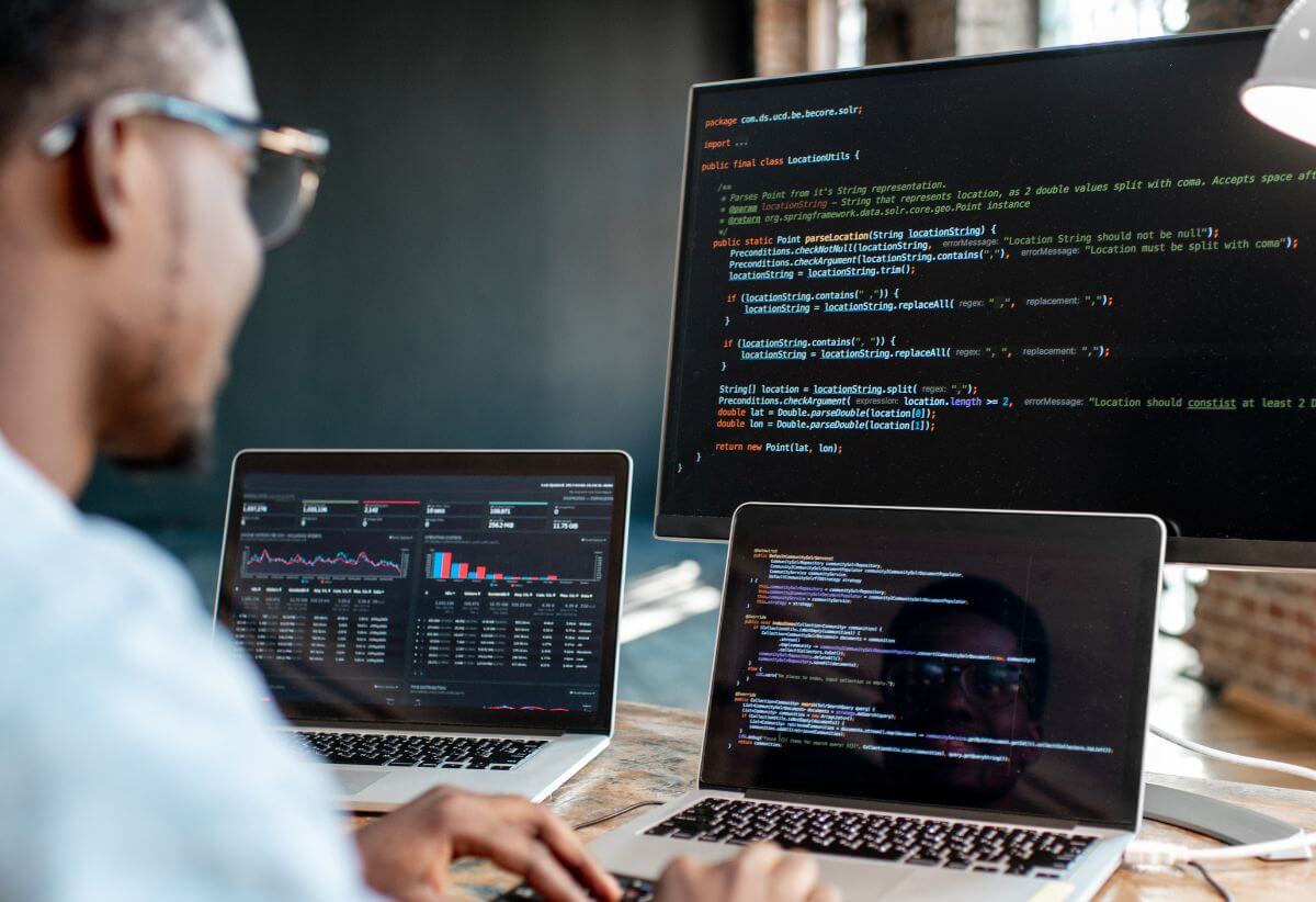 Person coding with three computers