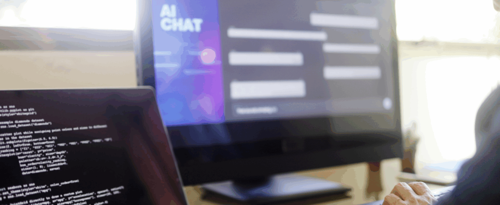 Two computer monitors, one with coding, the other with "AI Chat" on the screen.