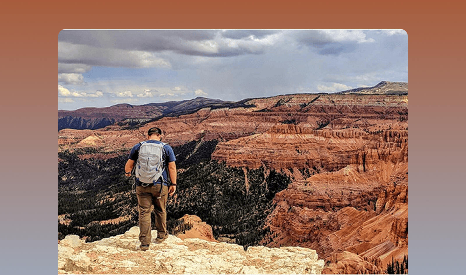 man near cliff edge overlooking mountains